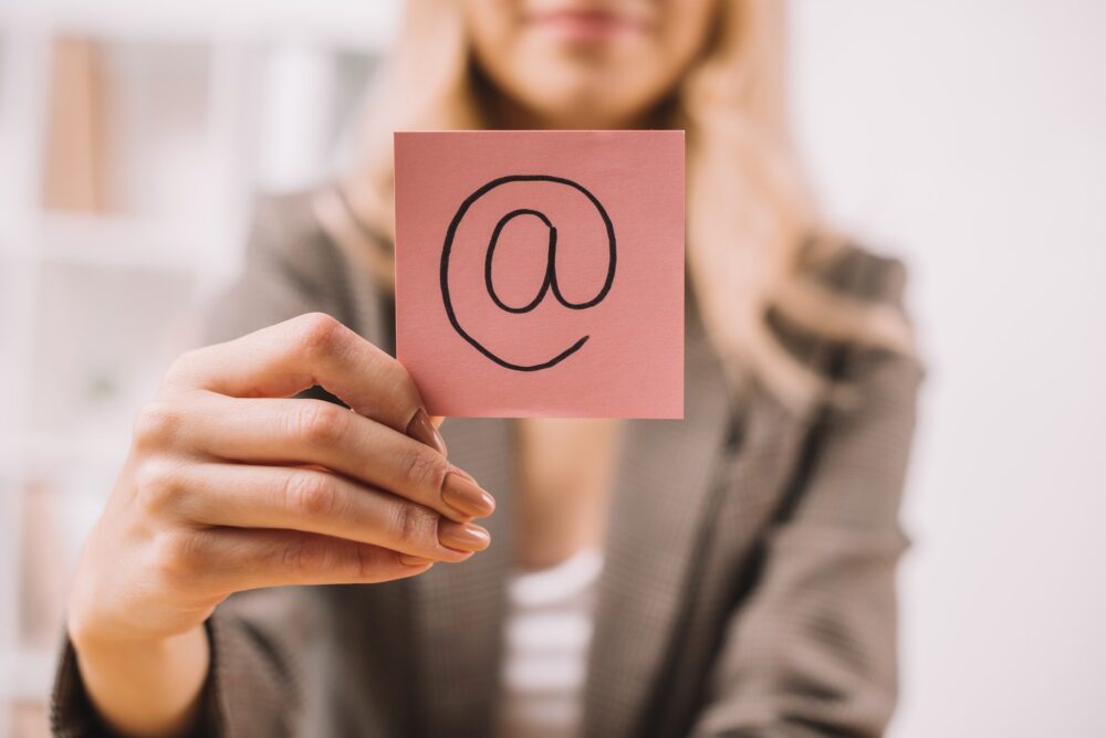 partial view of businesswoman holding paper note with email symbol