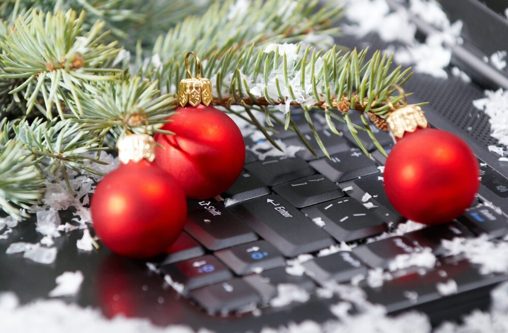 Christmas beautiful red balls with fir branch and snow on computer keyboard Christmas beautiful red balls with fir branch and snow on computer keyboard